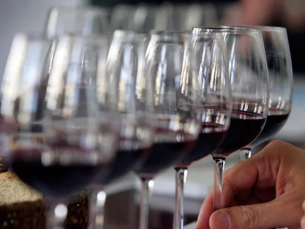 A row of red wine glasses being poured at the table